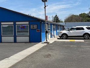 A blue building with a neon sign indicating it's open, a white car parked in front, and a 'No Smoking' sign. - Sunshine Inn (Yakima)