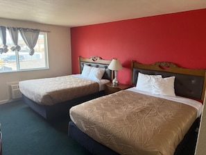 A hotel room with two beds, a red wall, and a window with curtains. - Sunshine Inn (Yakima)