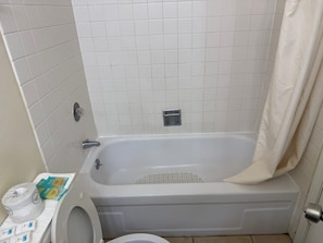 Une salle de bain avec une baignoire, des toilettes et un rideau de douche.
