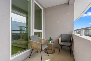 A balcony with two chairs, a small round table, and a potted plant.
