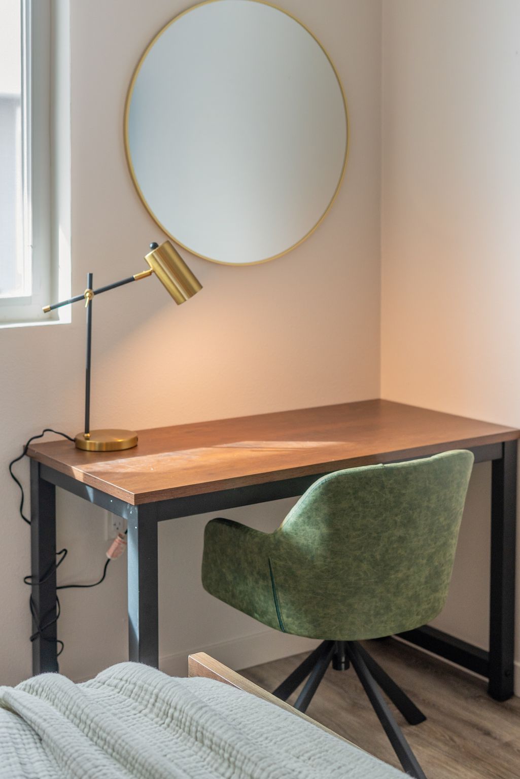 A study area with a desk, chair, and a round mirror on the wall.