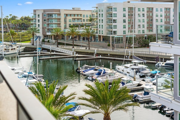 A marina with boats docked, a bridge, and modern buildings in the background.