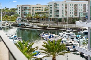 A marina with boats docked, a bridge, and modern buildings in the background.