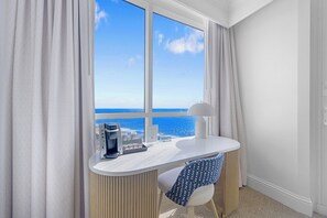 A hotel room with a view of the sea, a desk with a coffee machine, and a chair. - Oceanview Studio at Fontainebleau Miami Beach with Balcony (Miami Beach)