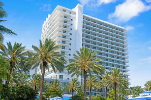 A multi-story hotel with balconies, surrounded by palm trees. - Oceanview Studio at Fontainebleau Miami Beach with Balcony (Miami Beach)