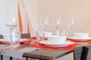 A dining table set with white plates, bowls, and clear glassware, including wine glasses and a water glass. - 2BR Maisonette | London Bridge | Near The Shard (London)