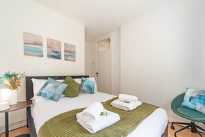 A hotel room with a bed, pillows, a bedside table with a lamp, and artwork on the wall. - 2BR Maisonette | London Bridge | Near The Shard (London)