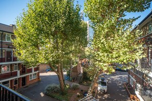 A residential street with a tree-lined road, a parked car, and multi-story buildings. - 2BR Maisonette | London Bridge | Near The Shard (London)