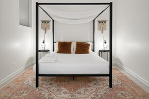 A four-poster bed with a white canopy, two fluffy pillows, and a matching throw on the footboard. - Elegant 2BR Apartment w/ In-Unit Laundry (Chicago)