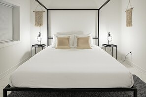 Een moderne slaapkamer met een groot bed, twee nachtkastjes en een raam met zonwering.