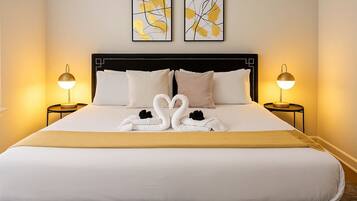 Quarto de hotel com uma cama grande, duas luminárias de cabeceira e duas pinturas abstratas na parede.