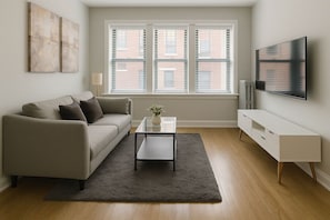 A living room with a sofa, coffee table, and TV. - Cozy 2BR Apt for a Seamless Stay (Chicago)