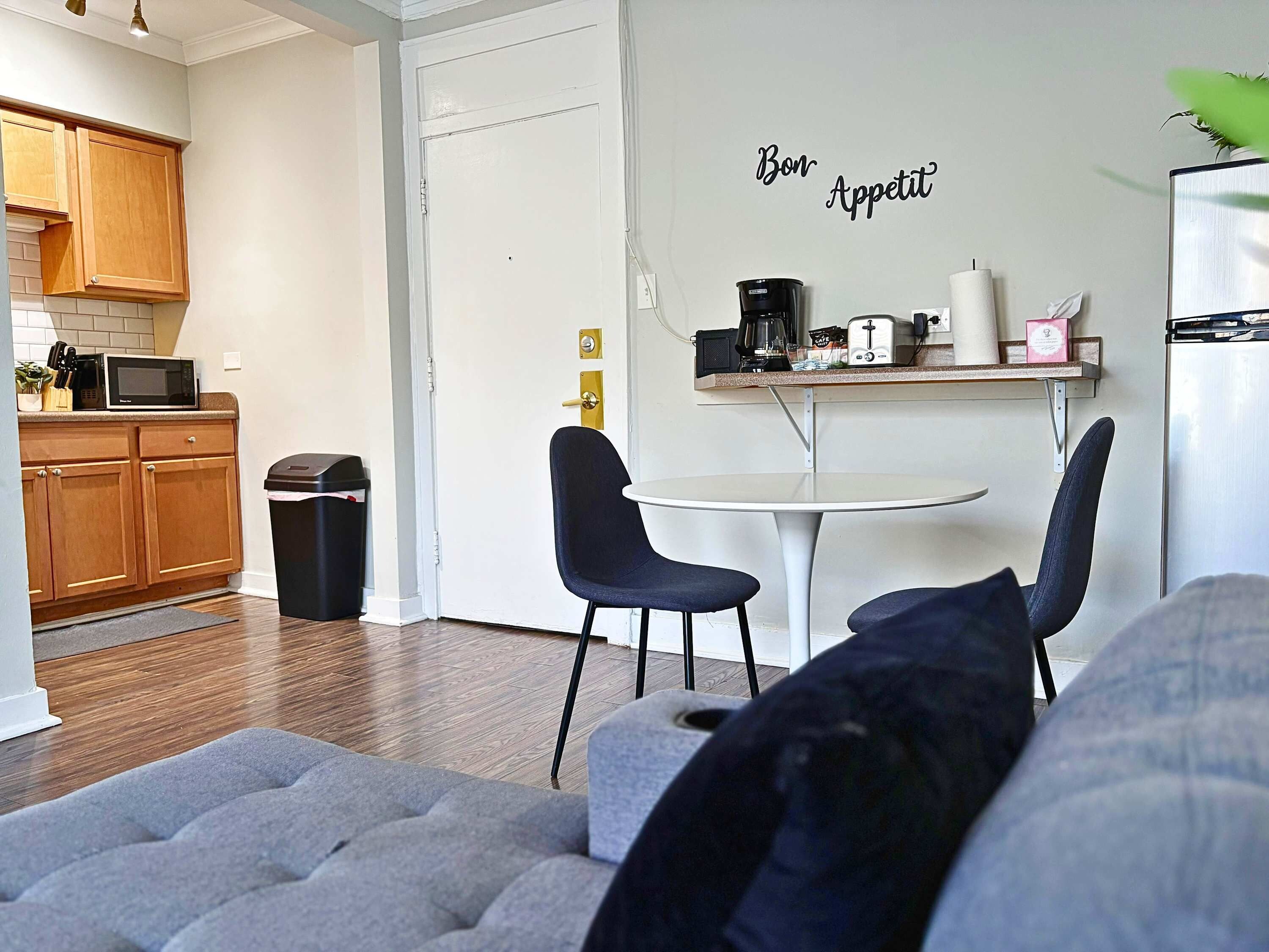 A compact living space with a kitchenette, a dining area with two chairs, and a sofa.