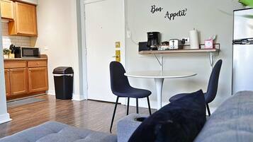 A compact living space with a kitchenette, a dining area with two chairs, and a sofa.