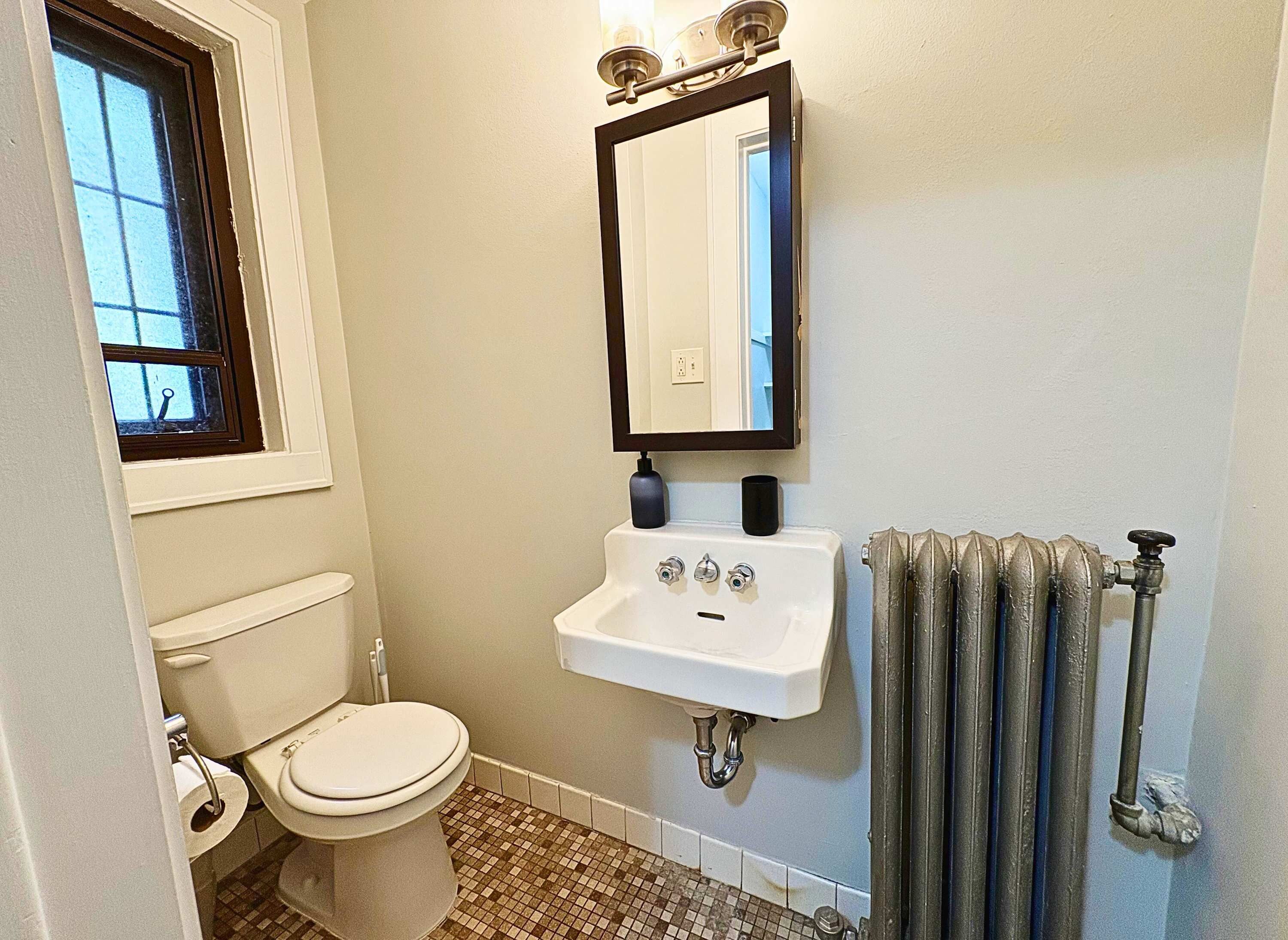 A bathroom with a toilet, sink, and radiator.