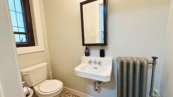 A bathroom with a toilet, sink, and radiator.
