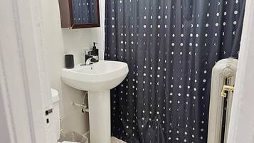 A bathroom with a white sink, a mirror above it, and a dark curtain with a moon pattern.