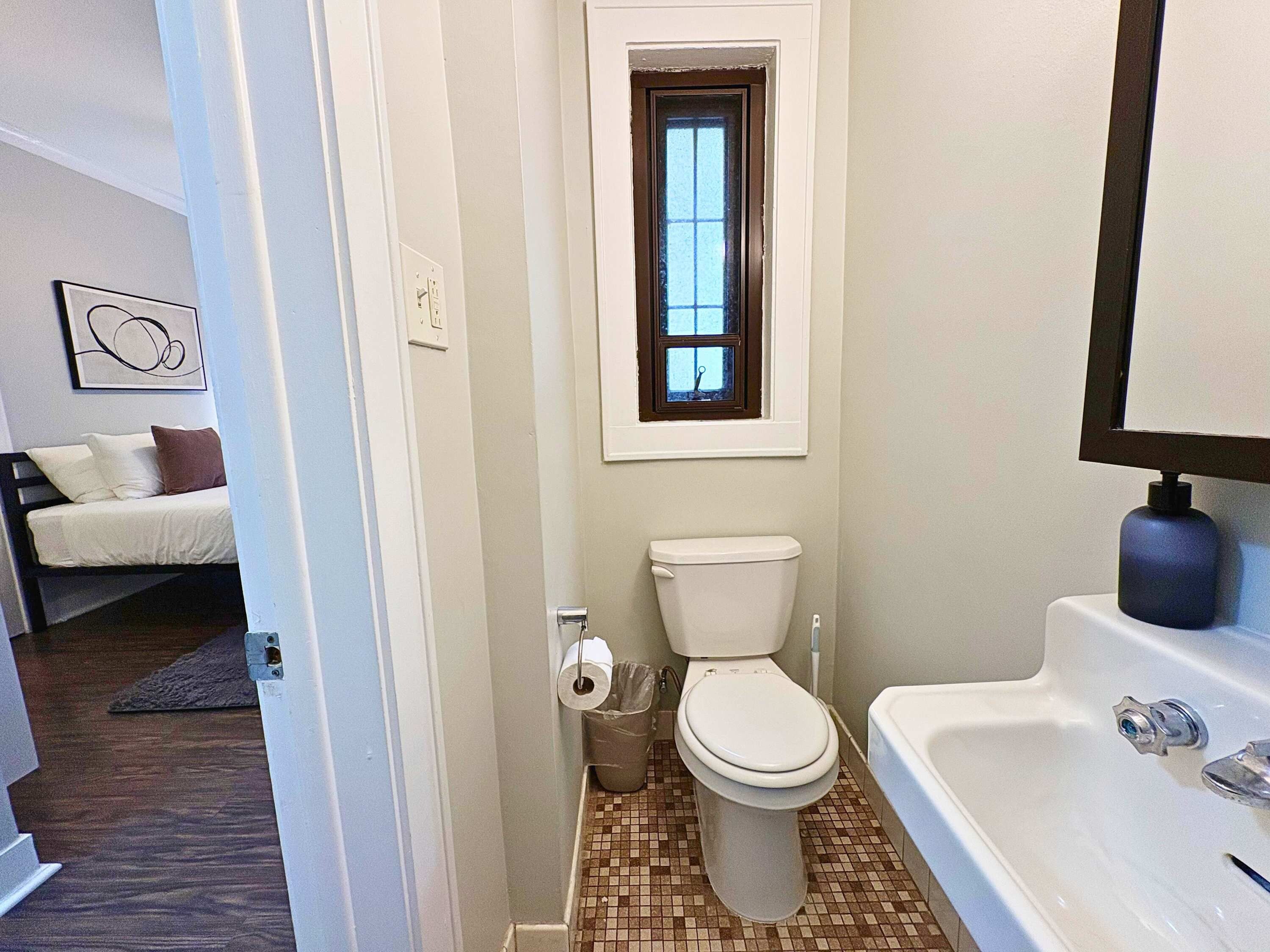 A compact bathroom with a toilet, sink, and window.
