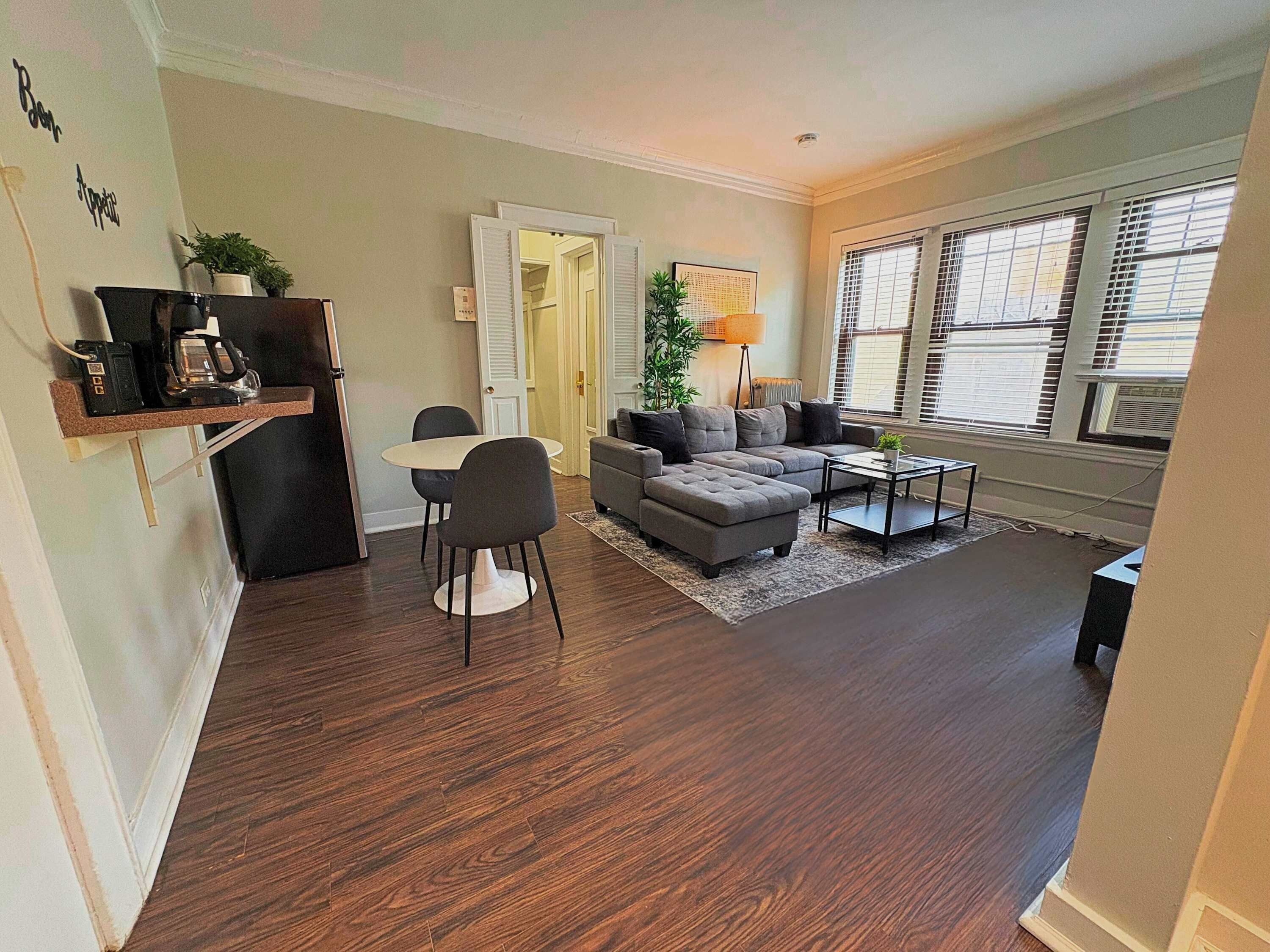 A living room with a sofa, coffee table, and a dining area with chairs.