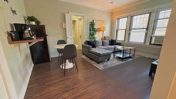 A living room with a sofa, coffee table, and a dining area with chairs.