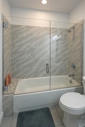 Une salle de bain moderne avec une douche à parois de verre, une baignoire blanche et des toilettes.
