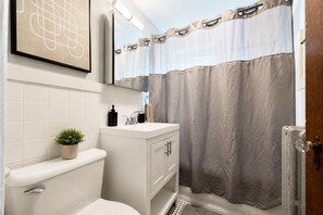 A bathroom with a toilet, sink, cabinet, and shower curtain.