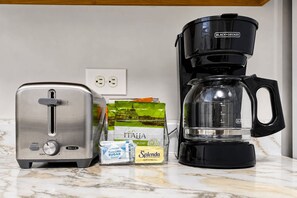 Una encimera de cocina con un tostador, una cafetera y un paquete de edulcorante Splenda.