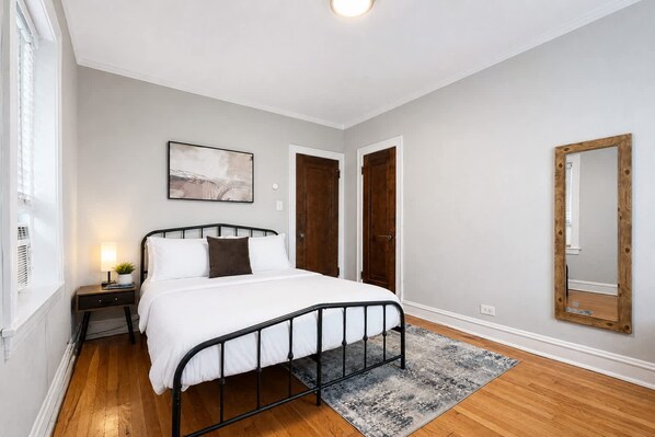 A bedroom with a bed, bedside table, lamp, and a painting on the wall.