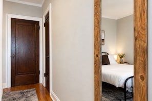Un dormitorio con cama, mesita de noche, lámpara y un cuadro en la pared.