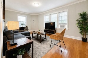 Una sala moderna con un sofá, una mesa de centro, un mueble para TV y una planta en maceta.