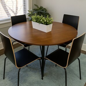 A round wooden table with a white planter in the center, surrounded by four black chairs with wooden accents. - 2BR Stylishly Apt in Lakeview (Chicago)