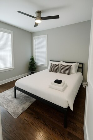 A bedroom with a bed, a ceiling fan, and a window with blinds. - 2BR Stylishly Apt in Lakeview (Chicago)