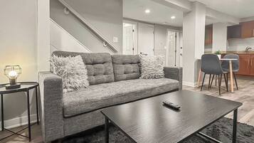 A modern living room with a grey sofa, a coffee table, and a small side table with a lamp.