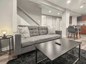 A modern living room with a grey sofa, a coffee table, and a small side table with a lamp. - Simple & Cozy 1BR Lakeview Apt (Chicago)