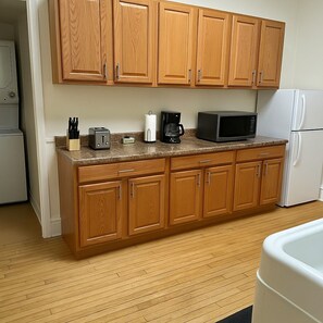 A kitchen with wooden cabinets, a granite countertop, a toaster, a coffee maker, a microwave, and a refrigerator.