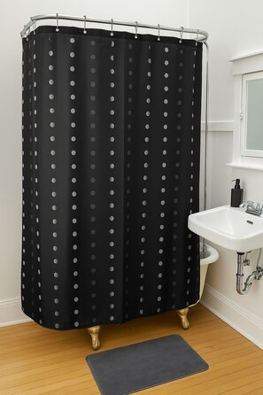 Ein Badezimmer mit schwarzem Duschvorhang mit Punkten, einem weißen Waschbecken und Holzboden.