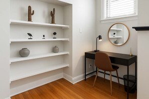 Una sala studio con una scrivania, una sedia, scaffali e uno specchio.