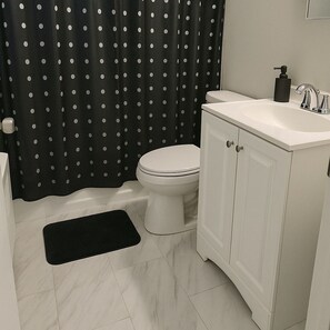 Une salle de bain avec des toilettes, un lavabo et un tapis noir sur le sol.