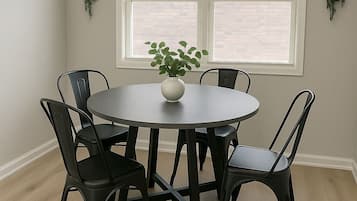 A dining area with a round table, black chairs, a white vase with a plant, and two wall-mounted planters.