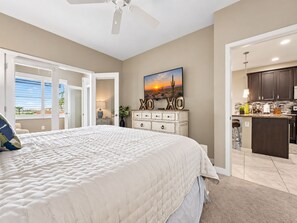 A bedroom with a large bed, a ceiling fan, and a painting of a sunset. - Luxury Living at the The Cays! Resort Pool/Spa, Steam, Gym. Waterfront Community! (Chandler)