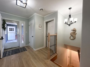 A hallway with a wooden floor, a staircase with a railing, and a door with a light fixture above it. - Charming 4-bedroom house on the Kishwaukee River in delightful Belvidere (Belvidere)