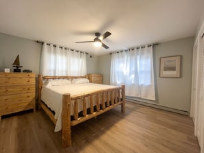 A bedroom with a wooden bed, a ceiling fan, and a window with curtains. - Charming 4-bedroom house on the Kishwaukee River in delightful Belvidere (Belvidere)