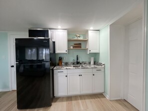 A compact kitchen with a black refrigerator, white cabinets, and a marble countertop. - Charming 4-bedroom house on the Kishwaukee River in delightful Belvidere (Belvidere)
