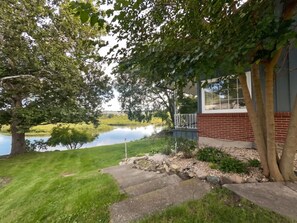 A house with a brick exterior, a pond, and a grassy area. - Charming 4-bedroom house on the Kishwaukee River in delightful Belvidere (Belvidere)