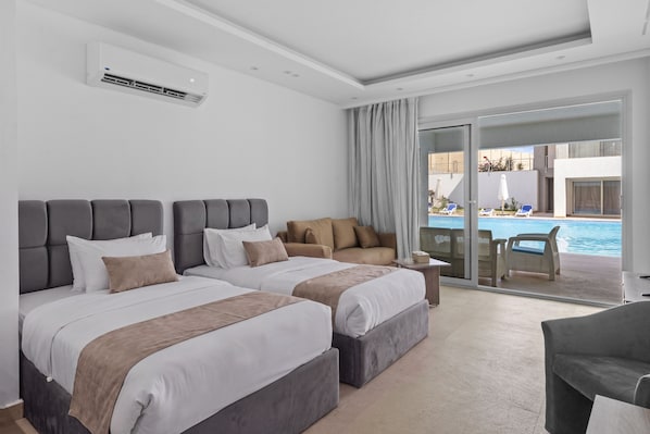 A hotel room with two beds, a sofa, a small table, and a view of a pool. - Maraya Pool Front Studio El Gouna (El Gouna)