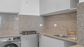 Cocina compacta con encimeras de granito, lavavajillas integrado y pileta de acero inoxidable.
