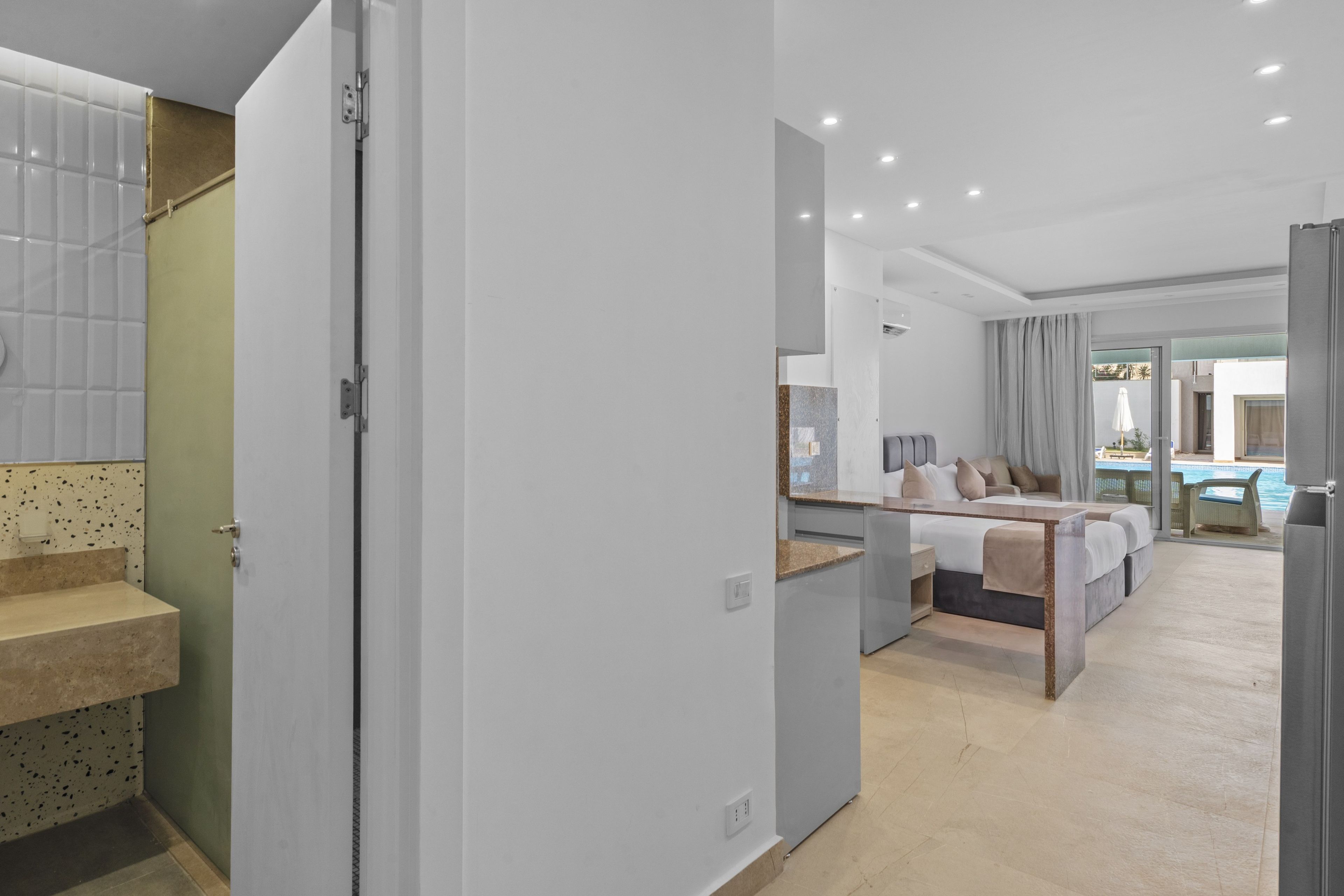Una habitación de hotel moderna con cama, baño y vistas a una piscina.