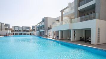 Et moderne hotel med swimmingpool, flere balkoner og udendørs siddeområder.