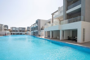 Et moderne hotel med swimmingpool, flere balkoner og udendørs siddeområder.