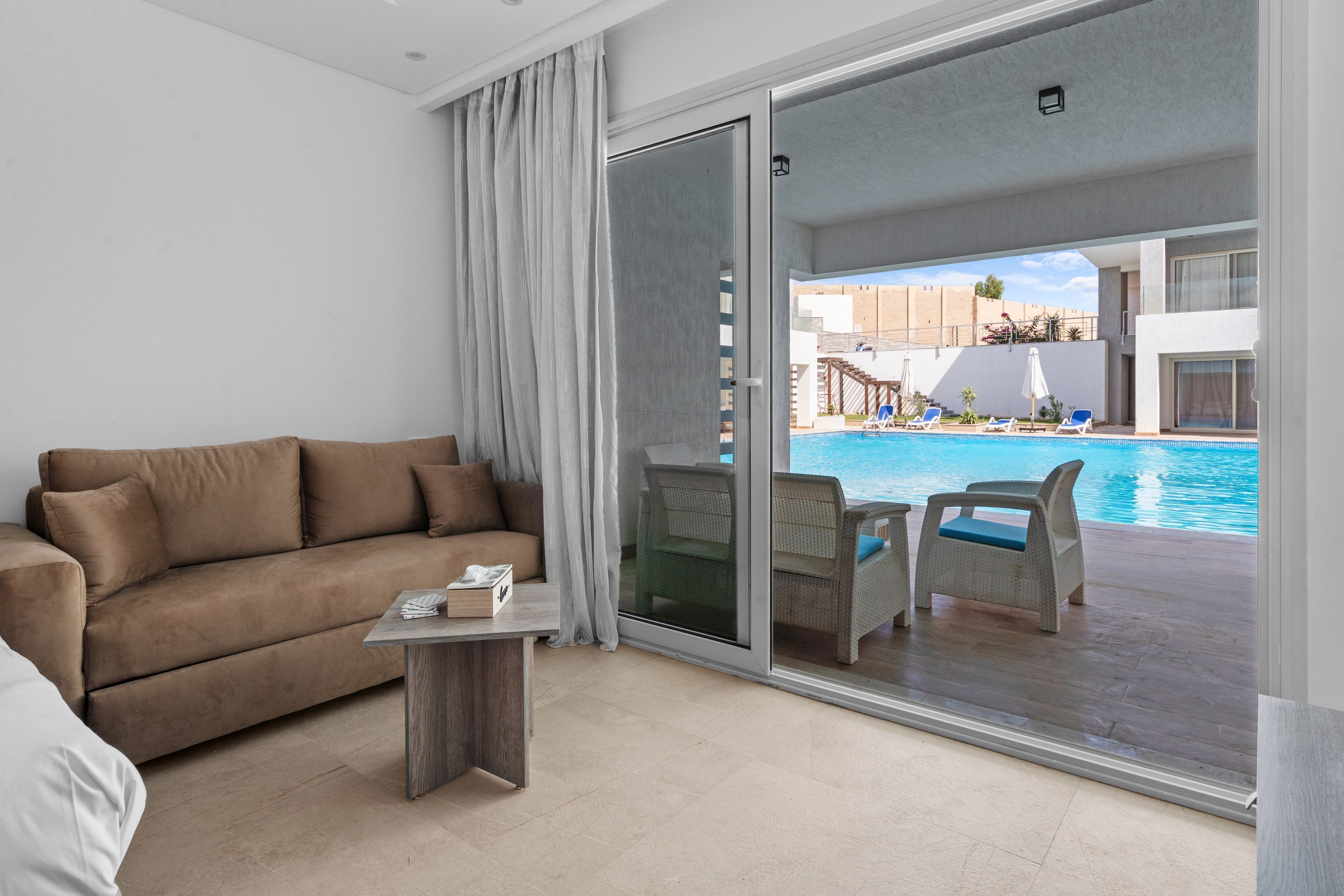 Habitación de hotel moderna con sofá, una mesita y vistas a una piscina.